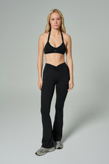 NALA Activewear black flared leggings and sports bra set; siyah İspanyol paça tayt ve spor sütyen giyen kadın model gri fonda önden tam boy duruyor.